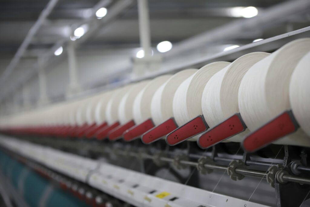 pexels photo 8246743 8246743 Close-up view of a textile production line showcasing white thread spools in an Indian factory.